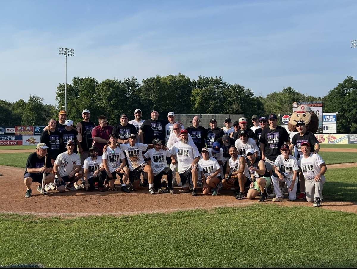 A large group in Rallying for Robert shirts posed on a baseball field.